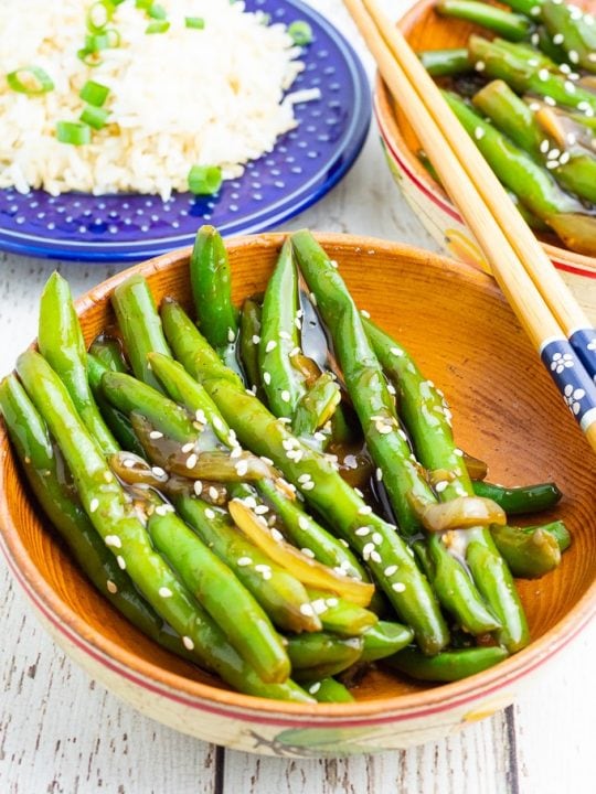 wooden bowl filled with green beans cooked in asian sauce
