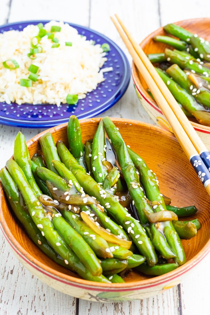 wooden bowl filled with green beans cooked in asian sauce