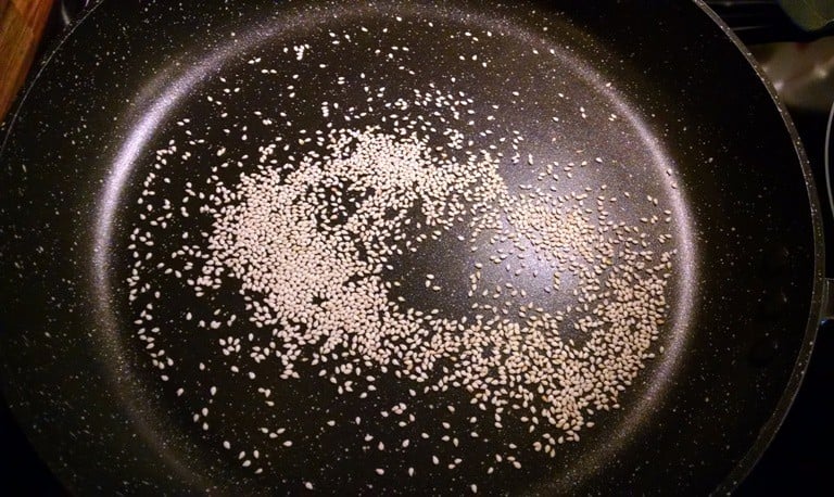 Sesame seeds being toasted in dry pan for chickpea veggie burgers