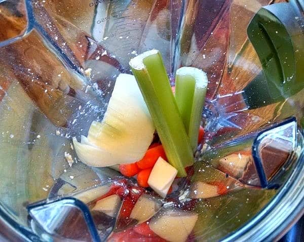 Onions, chickpeas, carrots, and celery being pulsed in blender for chickpea burgers