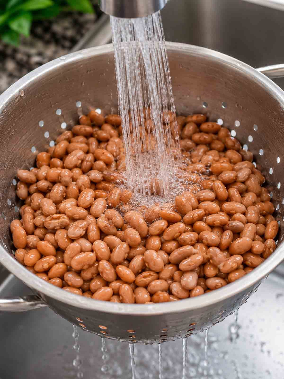 pinto beans being rinsed in a colander.