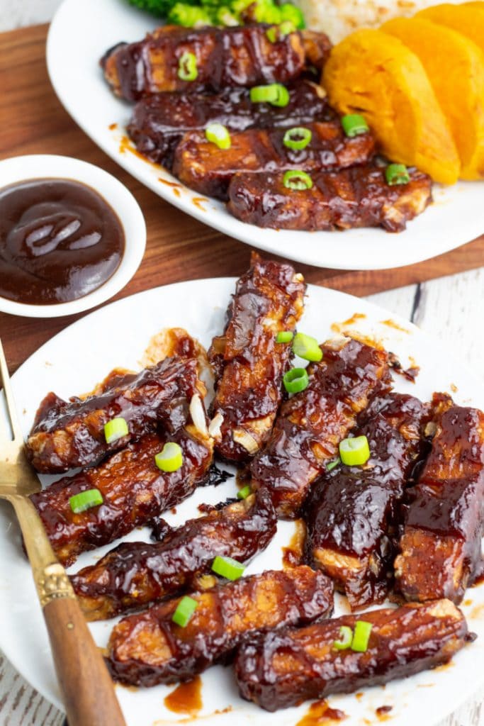 white plate with bbq tempeh strips and antique fork