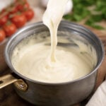 cashew mozzarella vegan cheese stretching in a saucepan on a fork.