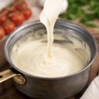 cashew mozzarella vegan cheese stretching in a saucepan on a fork.
