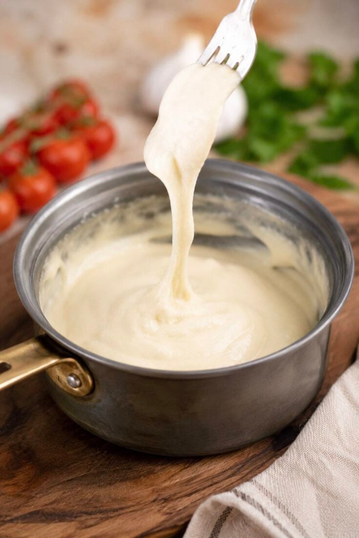 cashew mozzarella vegan cheese stretching in a saucepan on a fork.