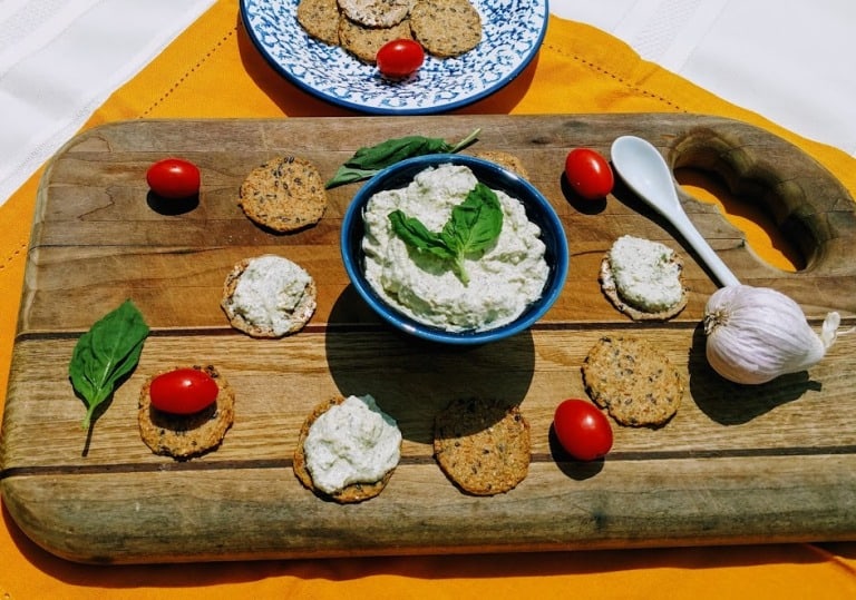 vegan ricotta in blue bowl. crackers and tomatoes on cutting board.