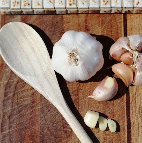 Garlic cloves and spoon on wooden board
