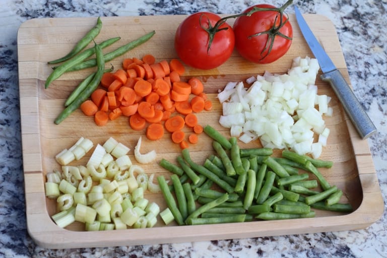 diced vegetables for vegan minestrone soup on a wooden cutting board.