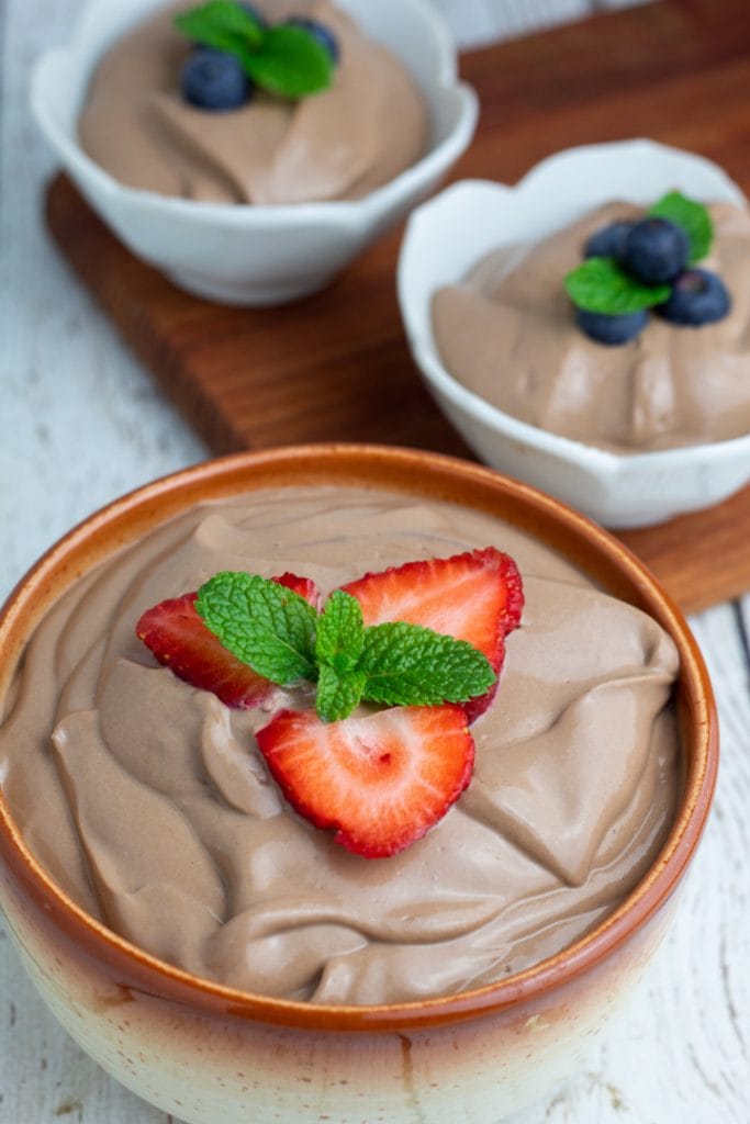 vegan chocolate mousse topped with strawberries and mint leaves