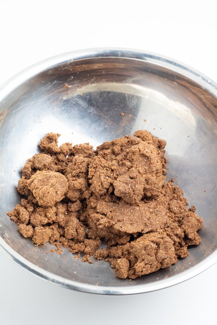 stainless bowl filled with vegan pie crust ingredients clumped up