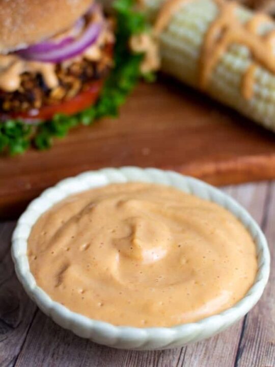 white sauce bowl filled with vegan chipotle sauce with burger in and corn