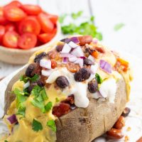 vegan potato taco on white plate with beans, vegan cheese, and sour cream