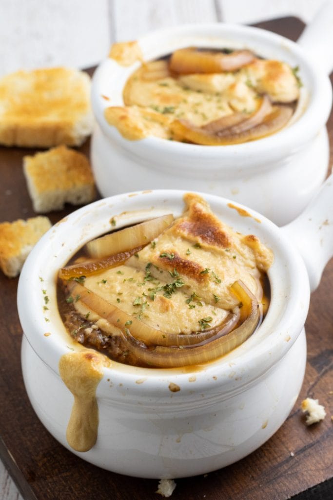 close up of vegan french onion soup in white crock bowl