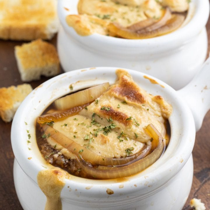 close up of vegan french onion soup in white crock bowl