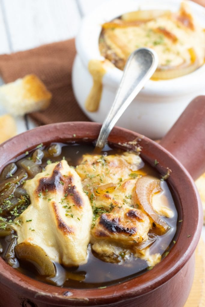 brown bowl with french onion soup and spoon