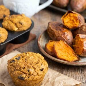 sweet potato muffin on brown parchment paper with baked sweet potatoes in background.