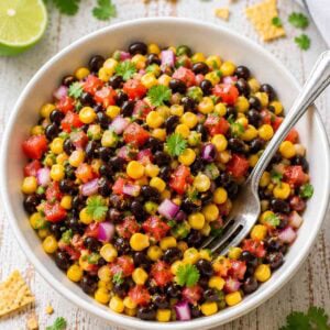 black bean corn salad in a whiite bowl with a fork.