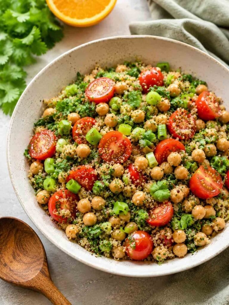 big bowl of chickpea quinoa salad with wooden spoon beside.