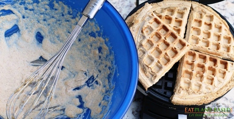 vegan waffles in waffle iron and batter bowl to the side