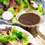 oil free salad dressing in clear glass cup surrounded by plates of salad