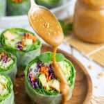 creamy peanut sauce being drizzled over a garden roll.