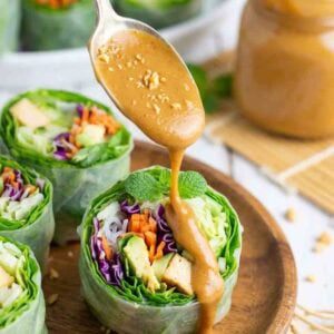 creamy peanut sauce being drizzled over a garden roll.