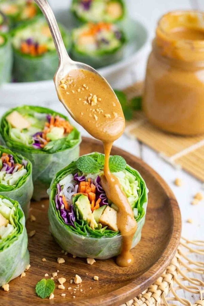 creamy peanut sauce being drizzled over a garden roll.
