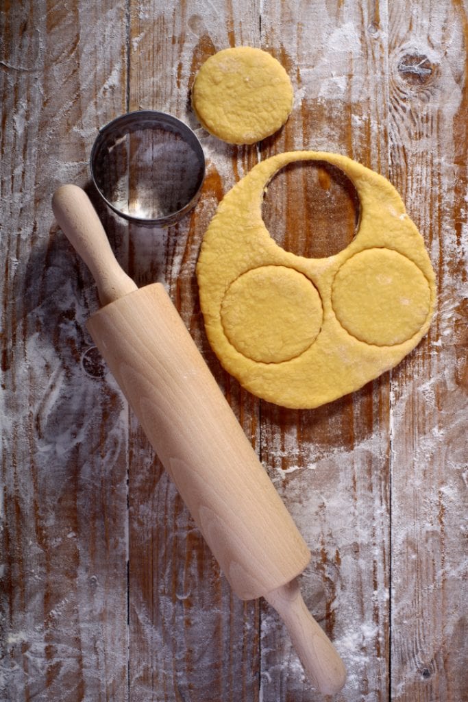 rolling pin, cookie cutter, and dough on wooden board