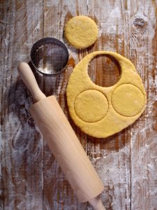 rolling pin, cookie cutter, and dough on wooden board