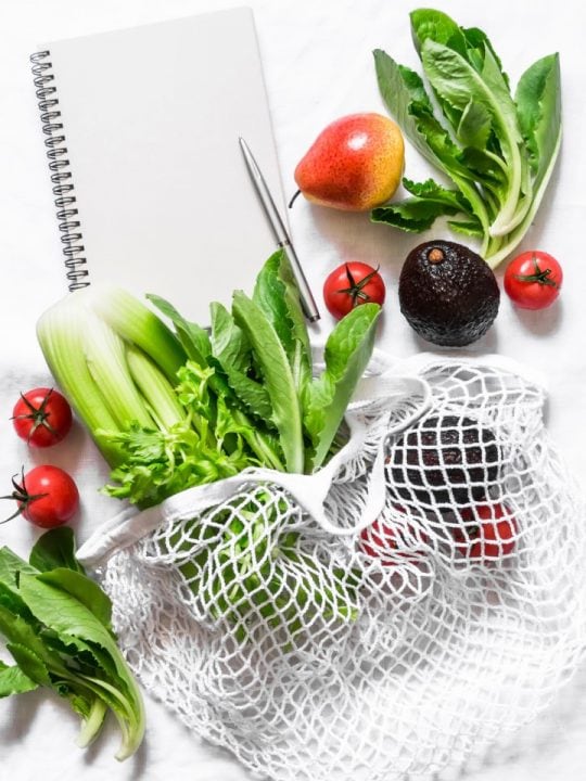 mesh grocery bag with veggies on white background