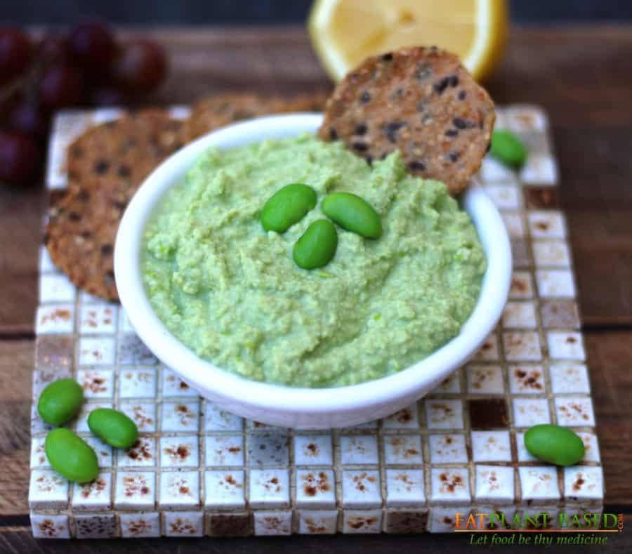 edamame hummus in white bowl with crackers