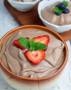 vegan chocolate mousse topped with strawberries and mint leaves