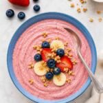 smoothie bowl topped with banana, strawberries, blueberries, and granola.