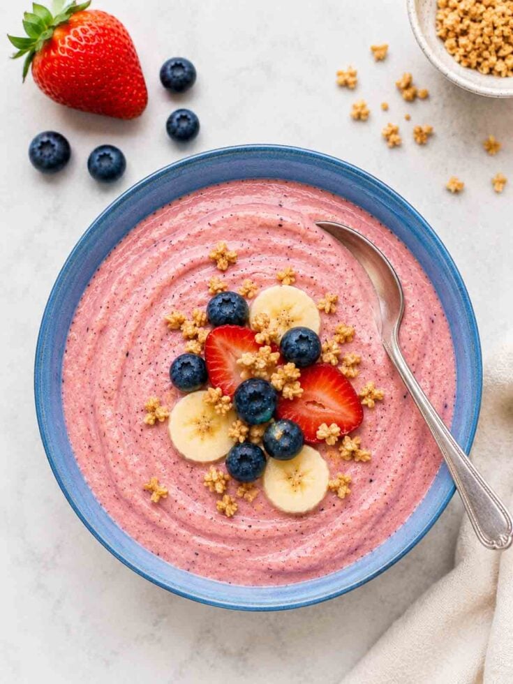 smoothie bowl topped with banana, strawberries, blueberries, and granola.