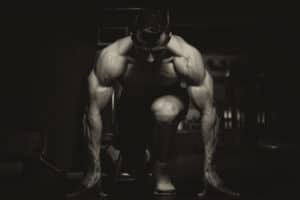 dark black and white photo of body builder squatting