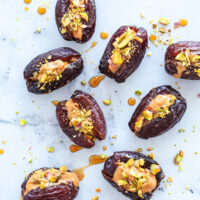 dates stuffed with peanut butter, nuts, and maple syrup on white counter top