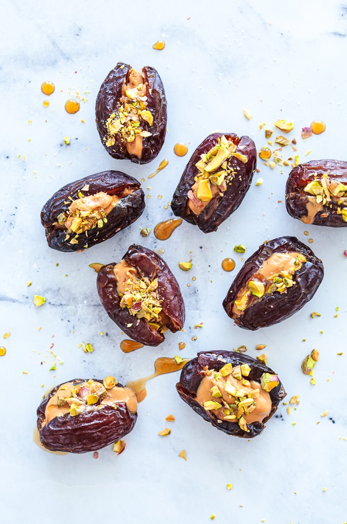 dates stuffed with peanut butter, nuts, and maple syrup on white counter top