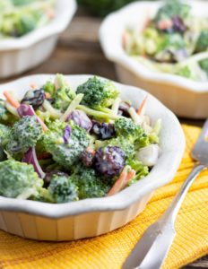 broccoli salad in white bowl on yellow napkin