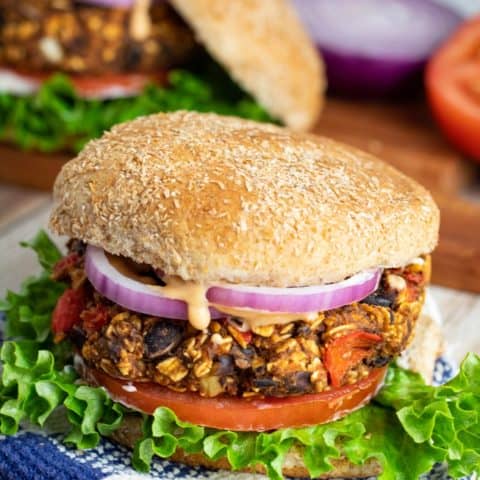 vegan black bean burger on a bun with lettuce, tomato, and onion