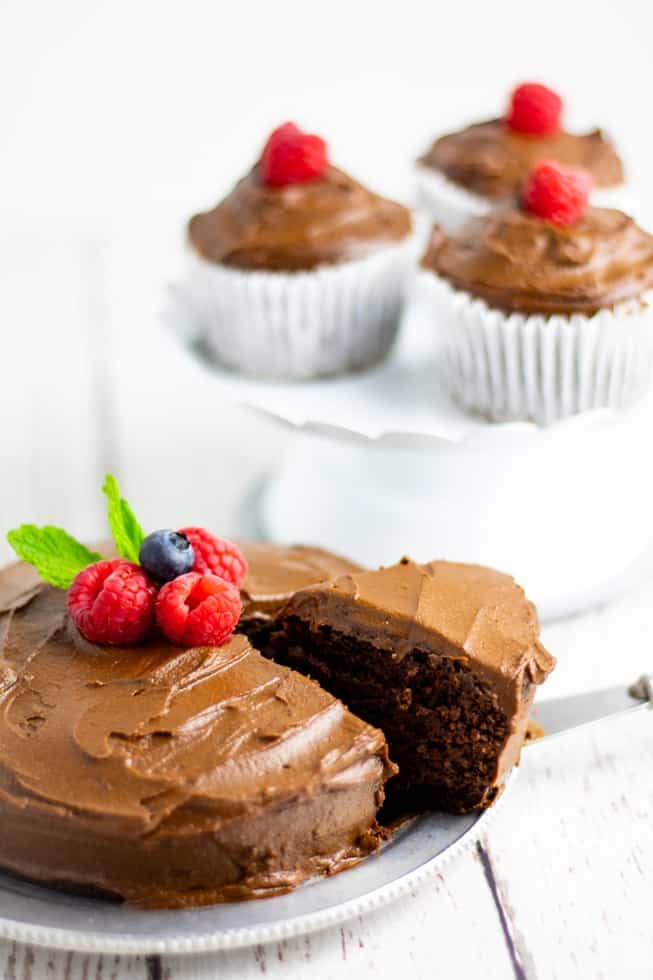 homemade sugar free cake being sliced on silver plate with cupcakes in background