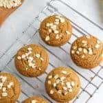 vegan muffins on cooling rack with oats sprinkled over the top on white background