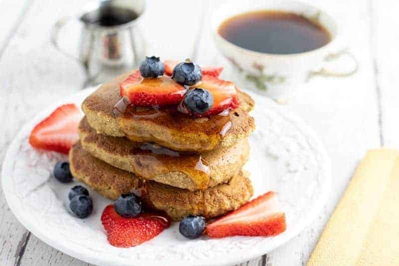Banana oatmeal pancakes topped with blueberries and strawberries on white plate