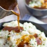 brown gravy being poured over mashed potatoes close up