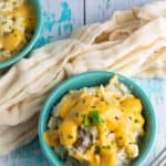 vegan mashed potatoes covered in dairy free cheese in aqua colored bowl on old stressed wooden tabletop