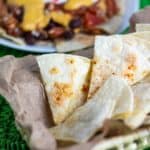 homemade tortilla chips in basket with nachos in background