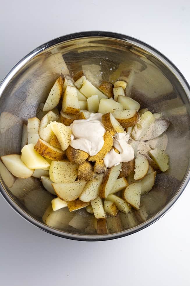 cooked potato slices with spices in stainless bowl