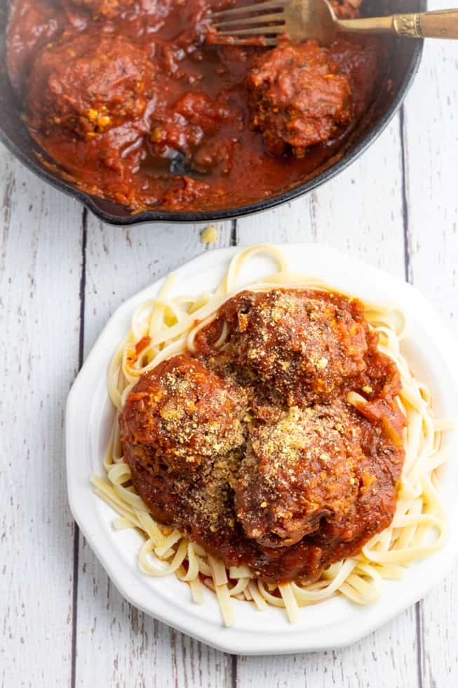 vegan meatballs on cooked pasta on white wooden table