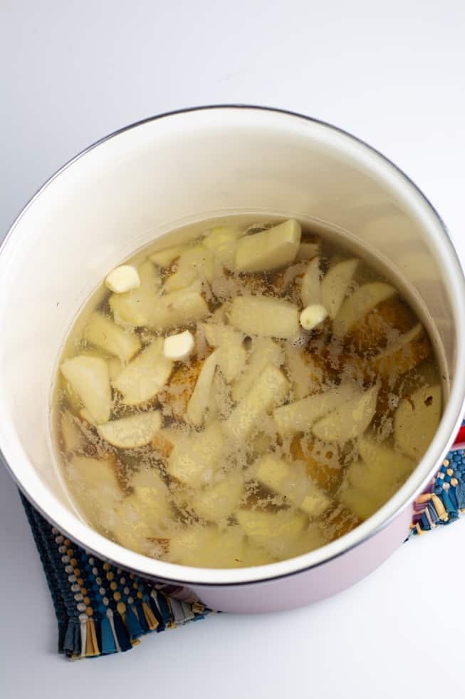 diced potatoes in pot of water on white background