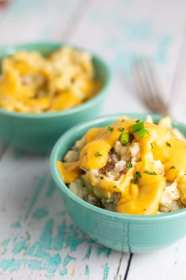 vegan mashed potatoes covered in dairy free cheese in aqua colored bowl