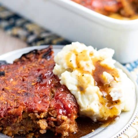 vegan meatloaf on silver plate with mashed potatoes and gravy